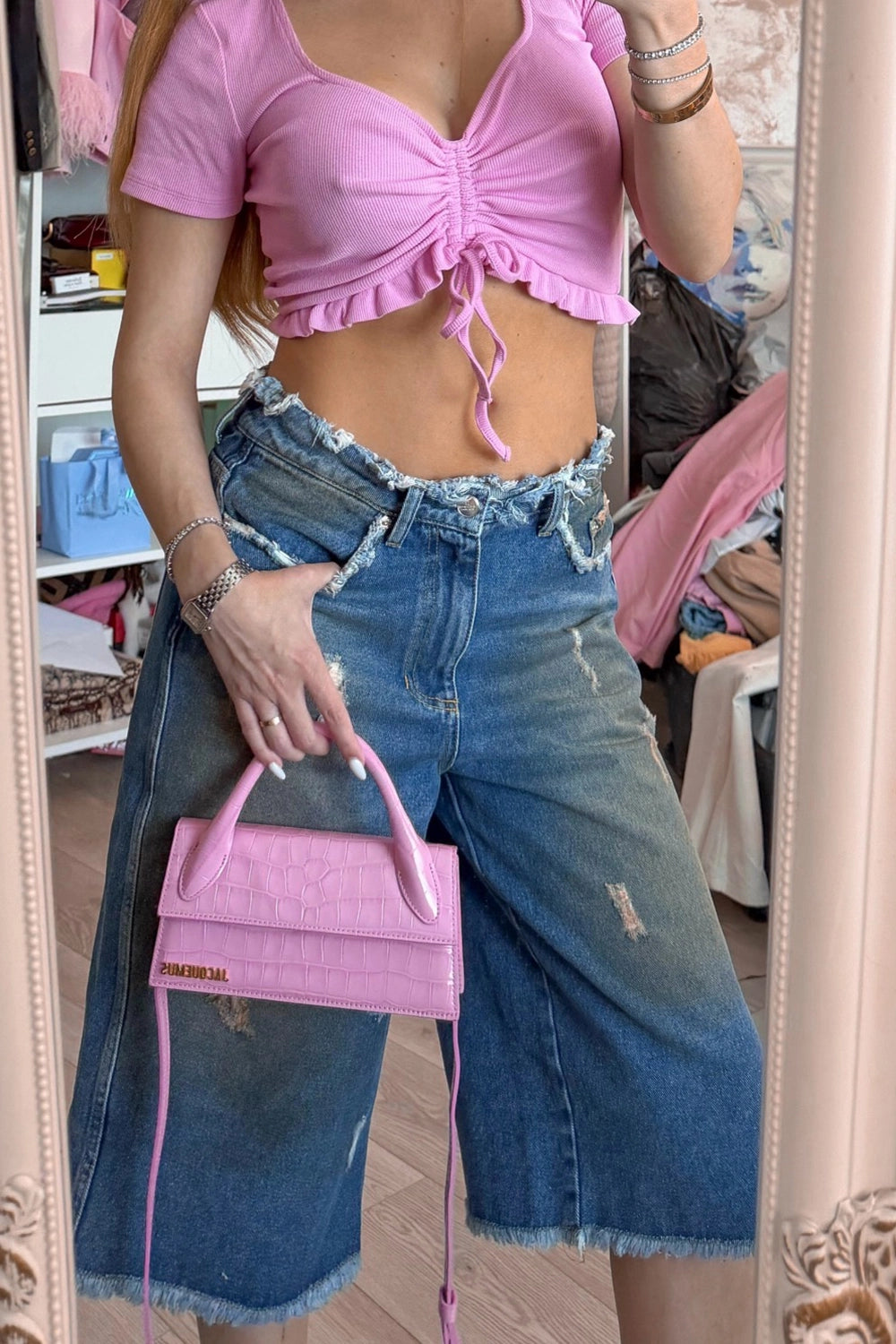 Model purtând bermude oversized din denim albastru cu talie joasă și aspect distressed.