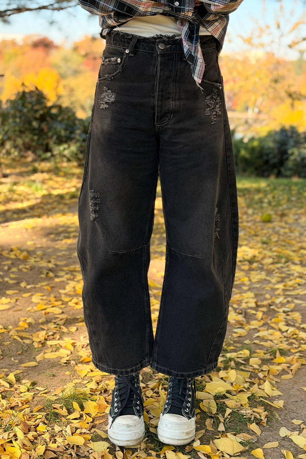 Blugi damă tip balon negri cu detalii destrămate și tiv scurtat tip cropped, purtați cu adidași negri și cămașă în carouri